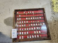 Top-down angle photo of the wooden display box with porcelain thimbles inside showing rows of detailed thimbles.