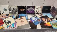Photo showing 21 vinyl record albums arranged in rows, mostly rock and pop with covers and titles visible such as Chicago, Steely Dan, Bee Gees, Commodores, Eagles, Bon Jovi, and ABBA.