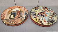 Two vintage round jigsaw puzzle tins showing detailed artwork, viewed from above