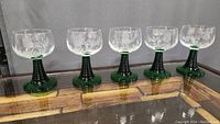Five vintage Luminarc wine glasses displayed in a row, showing green ribbed beehive stems and clear etched bowls.