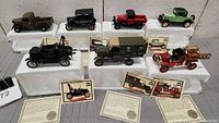 Full lot of 7 Ford Golden Age 1:32 scale diecast car and truck models arranged on white foam trays, showing variety of models and certificates of authenticity.