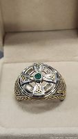 Front view of the sterling silver ring showing detailed Celtic cross design with an emerald in the center.