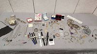 Wide view of jewelry and accessories laid out on a table including necklaces, watches, bracelets, earrings, rings, and pendants.