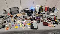 Full overview of men's jewelry, pins, lighters, keychains, sunglasses, and accessories laid on a surface