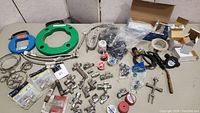 Full view of all plumbing parts, tools, clamps, tape, valves, fittings, and hoses spread out on a table.