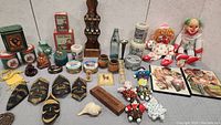 Full view of assorted vintage home decor items including masks, dolls, tins, pottery, wooden boxes, figurines, framed pictures.