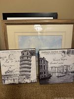 Framed watercolor and prints in a group, showing two Italian postcard prints in front with beige matting and framed watercolor behind