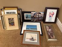 Group view of all framed art laid on floor showing variety of sizes, subjects, and frames
