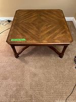 View of the top and legs of the square wooden coffee table showing surface pattern and condition.