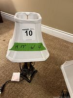 Close-up photo of one table lamp showing white fabric shade with taped measurement indicating 17 inches tall by 4 inches wide.