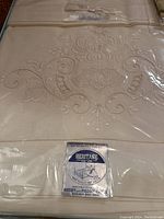 Cream linen bed set with intricate floral embroidery and lace in original packaging, labeled Heritage brand.