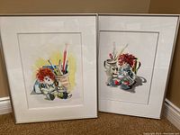 Two framed watercolor paintings of Raggedy Ann and Andy placed side by side, showing full artwork and frames.