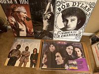 Photo showing all six posters standing on the floor, Guns N' Roses, David Lee Roth, Rush, Bob Dylan, The Kinks, The Doors.