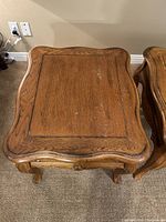 Top view of one oak end table showing slightly curved rectangular top with visible oak grain and minor surface marks.