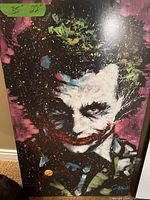 Signed print on board featuring Heath Ledger's Joker with colorful splatter paint effects and intense expression, showing measurement sticker 35 x 22.