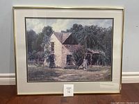 Framed art print signed by J. Dudley showing a stone house with greenery and a person walking. Full view of the framed piece.