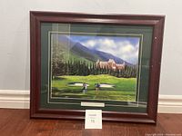 Framed artwork showing two golfers playing on a green at Banff Spring Golf Course, visible signature and plaque, wooden frame with wear.