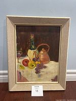 Full view of the framed still life painting with a textured off-white frame and visible wear