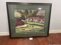 Full view of the framed Augusta National Golf Course art print with golfers on the green and colorful azaleas.
