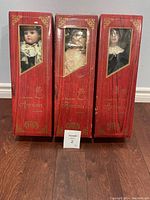 Three original red boxes for CHSN Artisan Collection porcelain dolls, some wear visible