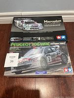 Two Tamiya model kit boxes stacked showing Mercedes CLK-GTR and Peugeot 206 WRC 2002 model kits with original box art.