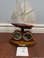 Front view of the wooden base with the sailboat model, clock and thermometer. Clock and thermometer dials clearly visible, clock showing time correctly.