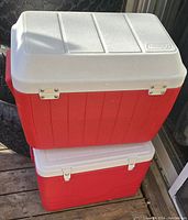 Two stacked Coleman coolers, larger cooler on top with hinged lid and metal reinforcements