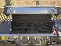 Open grill top showing six burners, cooking grates and warming rack
