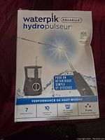 Front of Waterpik Aquarius Hydropulseur water flosser box showing model WP-660, pressure settings, and included tips.