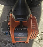 Close-up of the orange and black Remington Rustler RM2530 label and pull start mechanism on the trimmer