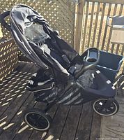 Side view of black Evenflo jogging stroller with visible wheels, seating area, and canopy.