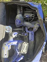 Kobalt cordless power tools including reciprocating saw and jigsaw inside branded blue and black tool bag with charger and power cords visible.