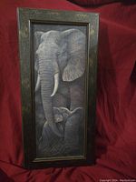 Front view of the framed mother and baby elephant photo against red cloth background.