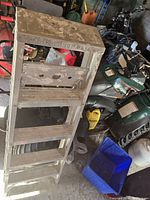 Close-up image of 5-foot painter's step ladder showing metal frame, wooden steps, and top section with tool slots and paint stains.