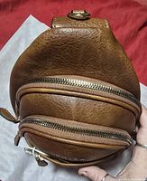 Side view of the tan Prite cross body bag showing the texture, multiple zippered compartments and top of the adjustable strap.