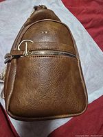 Front view of the tan Prite cross body bag showing textured leather and front zipper pocket.