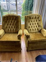 Pair of green gold velvet swivel upholstered rocking chairs with tufted backs and cushioned armrests.