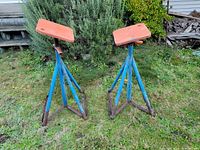 Two assembled tripod boat stands on grass showing wooden top plates and steel legs