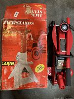 Photo of the Pittsburgh compact trolley jack next to one red Larin jack stand box.