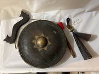 Metal Thai gong with central raised boss, geometric star design, carved wooden handle, and padded mallet.