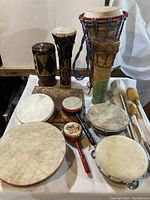 Overview of various drums, tambourines, and mallets arranged on a table.