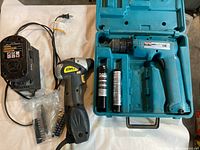 Makita cordless driver drill in blue plastic hard case with two cylindrical batteries, Chicago Electric drill, battery charger, and assorted screwdriver and drill bits