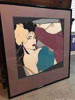 Full view of the Patrick Nagel framed serigraph print showing the image of a woman with black hair, yellow flower, blue top, with purple matting and black frame.