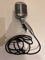 Front view of the Shure 55SW microphone showing metal grille and attached cord.