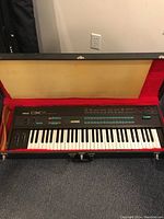 Yamaha DX7 inside red velvet-lined hard case showing full keyboard and included case