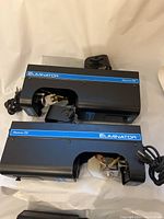 Two American DJ Eliminator theater lights showing black metal casing with blue stripe and vent fan on side.