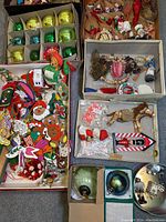 Full lot overview showing multiple boxes of assorted Christmas tree ornaments including various vintage balls, wooden, fabric, straw figures, and other holiday decorations.