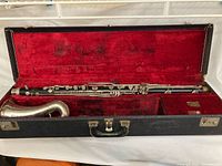 Clarinet assembled in open black hard case with red velvet interior showing body, curved neck, and bell