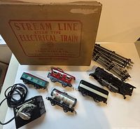 Vintage electric train set by Louis Marx & Co., train cars, transformer and track pieces arranged with original box