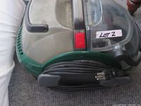 Side view showing the power cord wrapped around the cleaner, red power button, and handle on top.